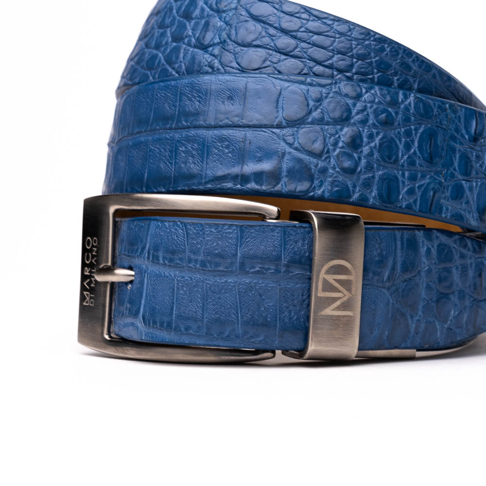 The Riccardo Belt Blue by Marco Di Milano features a caiman fuscus belly with crocodile pattern and a silver buckle engraved with "Marco Di Milano" and "MDM," making it ideal to pair with luxury footwear.