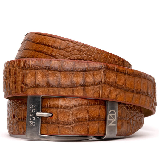 The Riccardo Belt Cognac by Marco Di Milano is a luxury exotic belt made from genuine caiman belly leather with a crocodile pattern and features a silver buckle engraved with the brand’s logo and signature.
