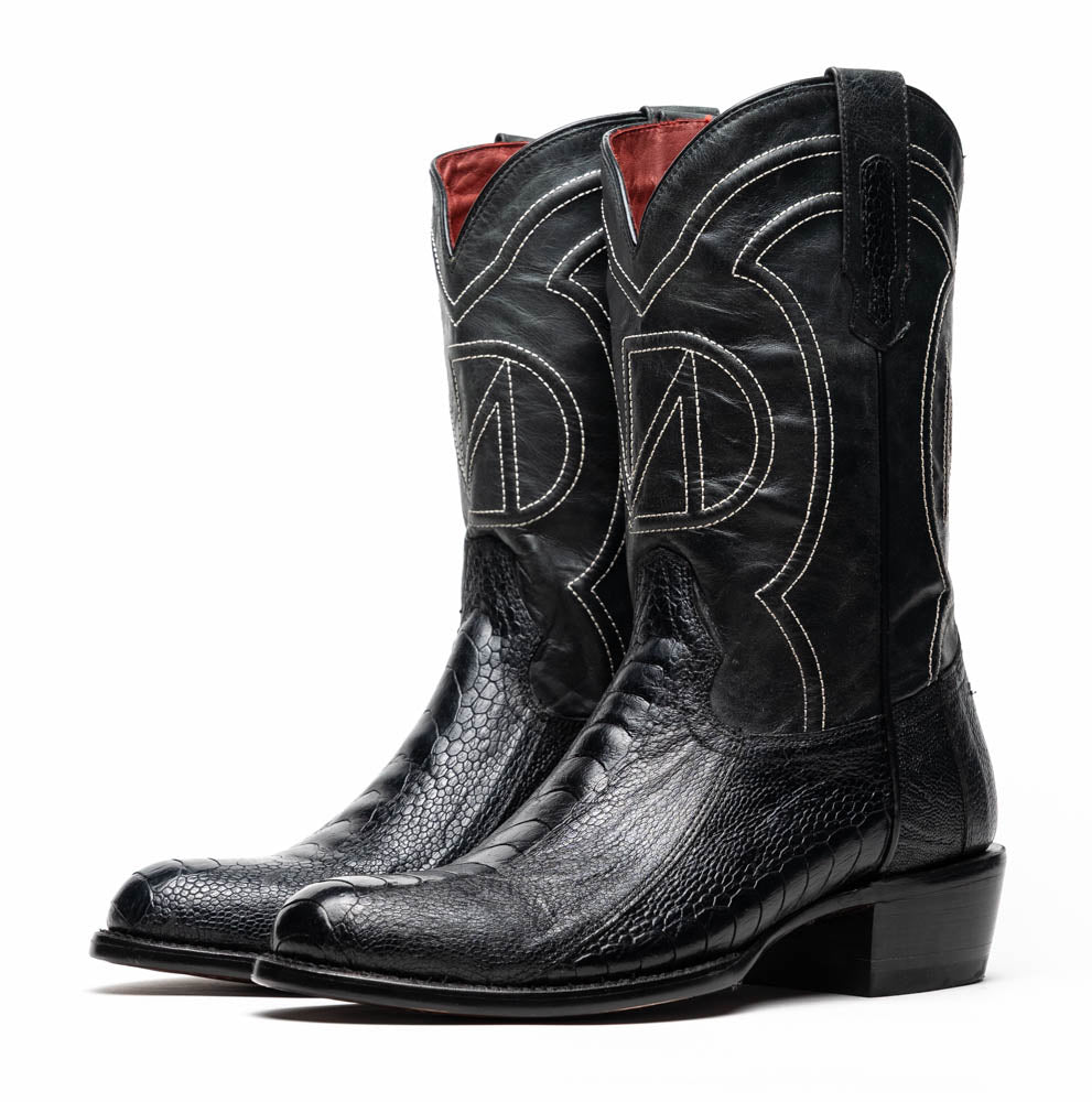 A pair of Denver Black cowboy boots by Marco Di Milano in genuine black ostrich leather, one upright and one displaying the sole with white stitching and the Marco Di Milano logo.