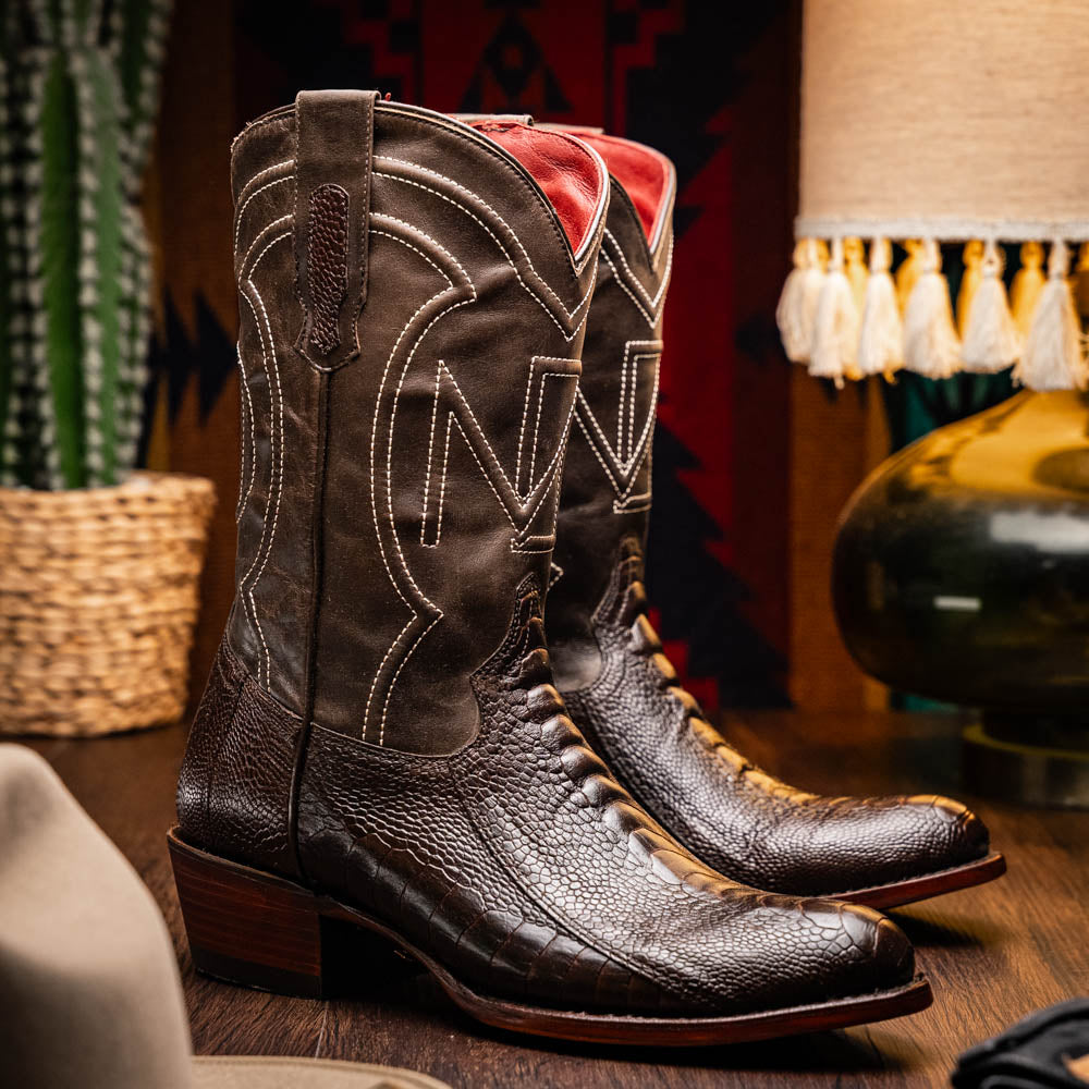 A pair of Denver Brown Western boots by Marco Di Milano in dark brown textured leather, featuring contrast stitching and genuine ostrich style; one boot shows the branded sole.