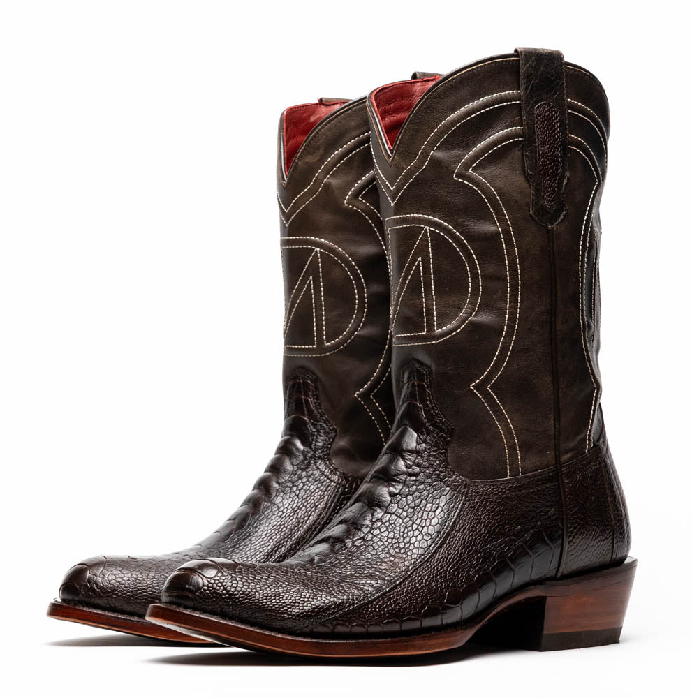 A pair of Denver Brown Western boots by Marco Di Milano in dark brown textured leather, featuring contrast stitching and genuine ostrich style; one boot shows the branded sole.