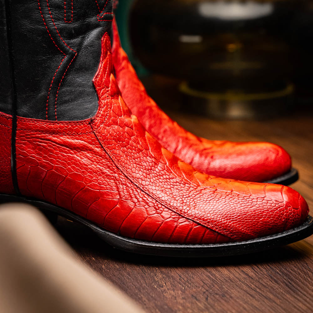 The Denver Red boots by Marco Di Milano feature bold red and black genuine ostrich skin—one boot upright, one showing the sole with the signature logo—for a striking, luxurious Western style.