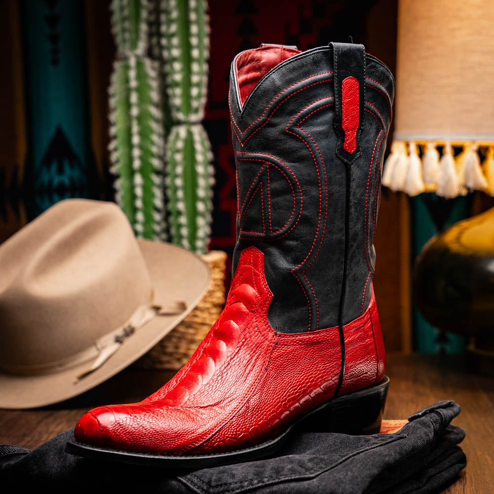 The Denver Red boots by Marco Di Milano feature bold red and black genuine ostrich skin—one boot upright, one showing the sole with the signature logo—for a striking, luxurious Western style.