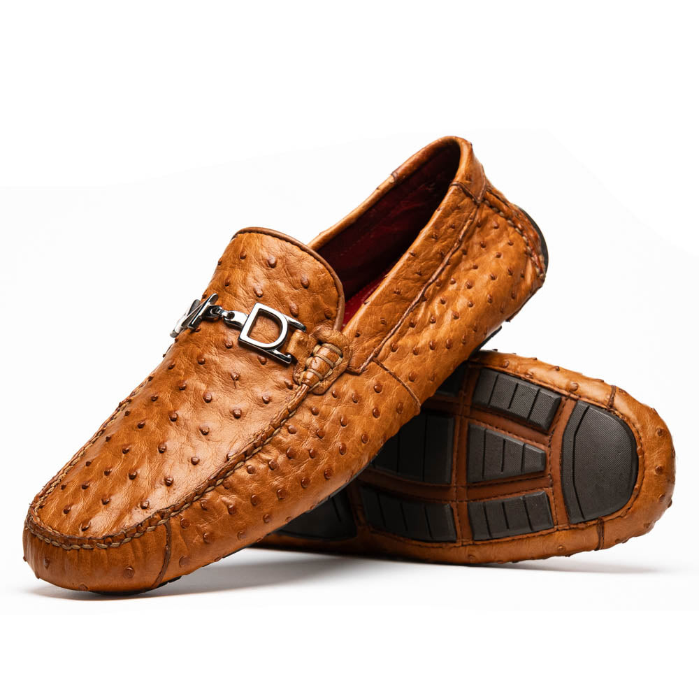 The Bolonia Brandy by Marco Di Milano—brown ostrich leather loafers with hand-painted finishes and metal buckles, one upright and one on its side revealing the sole—exude luxury, crafted from genuine exotic leather.