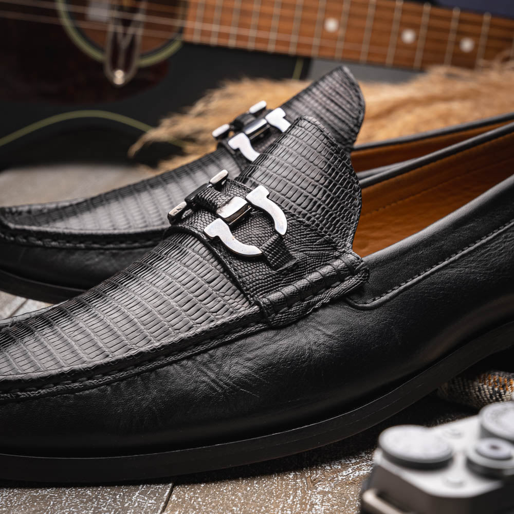 The Enzo Black by Marco Di Milano: black textured genuine lizard loafers with metal bit detail—one upright, one showing a brown sole stamped with "MARCO DI MILANO"—perfect for fans of luxury men's footwear.