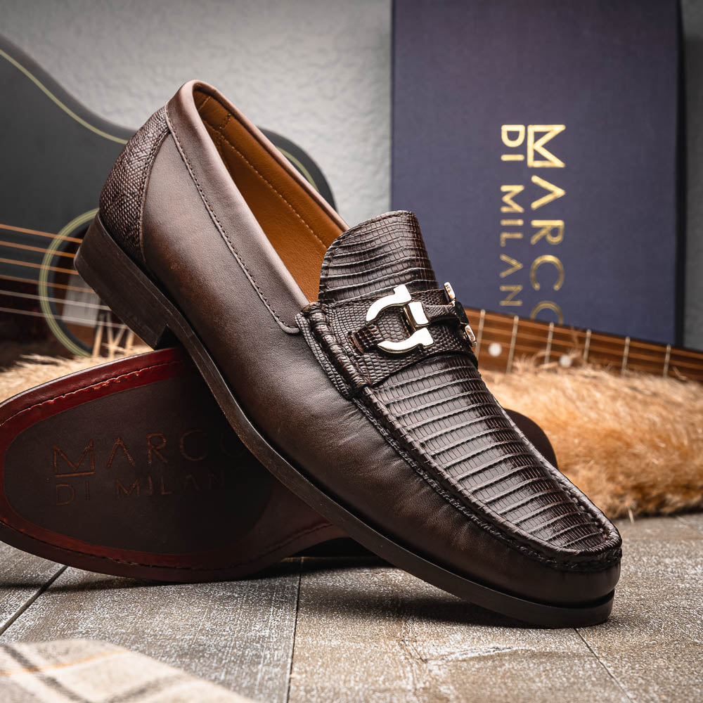 The Enzo Brown by Marco Di Milano features dark brown genuine lizard loafers with textured uppers, a metal buckle, and branded soles—luxurious men's footwear displayed against a white background.