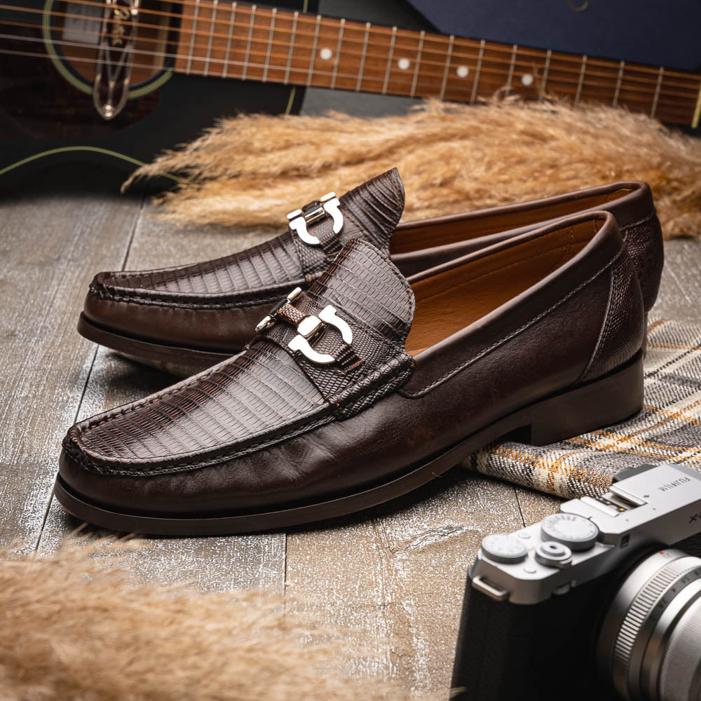The Enzo Brown by Marco Di Milano features dark brown genuine lizard loafers with textured uppers, a metal buckle, and branded soles—luxurious men's footwear displayed against a white background.