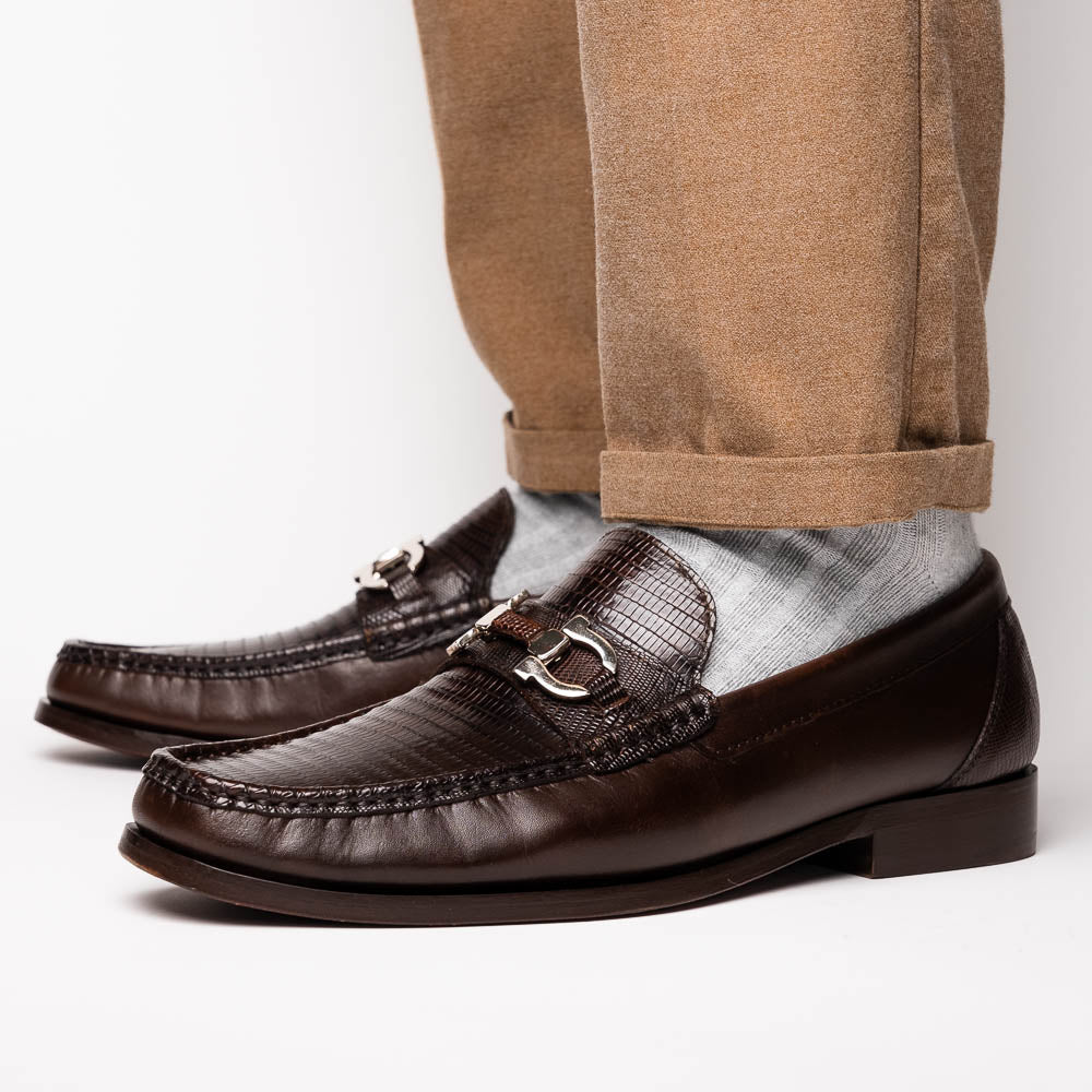 The Enzo Brown by Marco Di Milano features dark brown genuine lizard loafers with textured uppers, a metal buckle, and branded soles—luxurious men's footwear displayed against a white background.