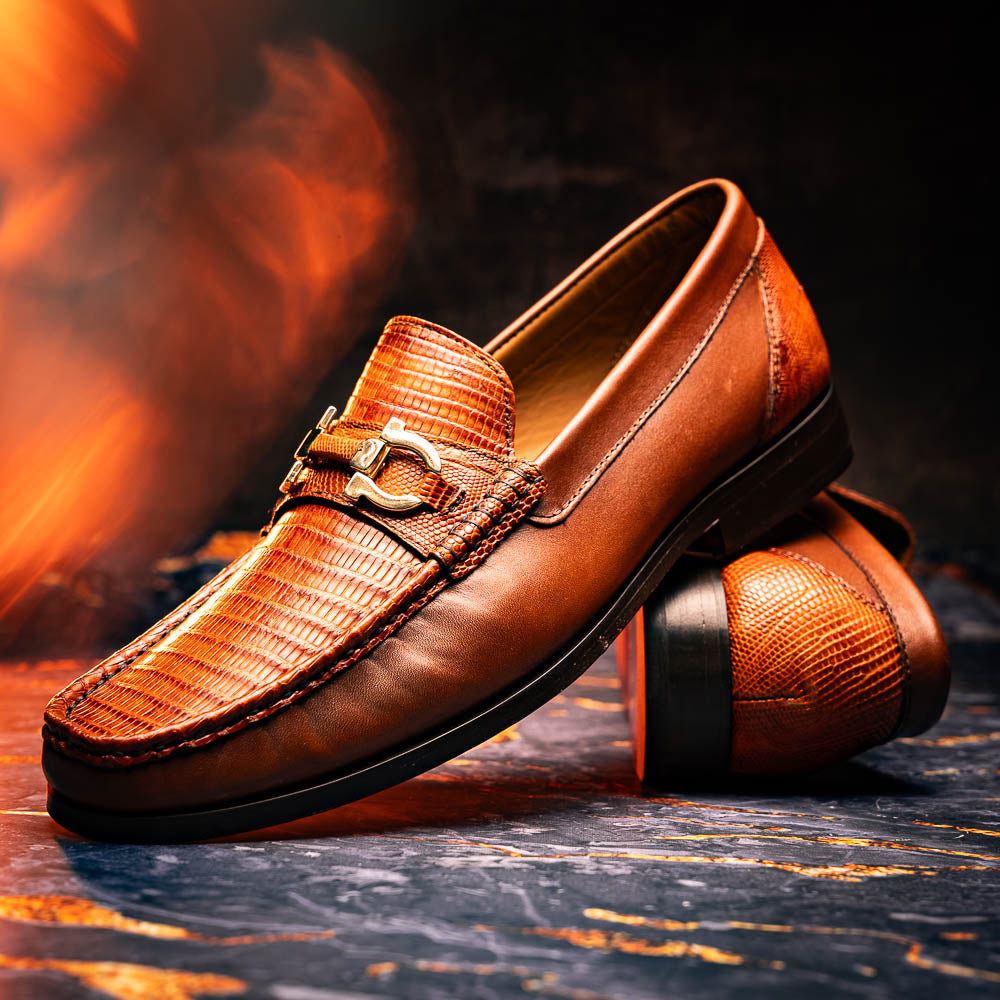 The Enzo Cognac by Marco Di Milano: men's brown leather loafers with a textured pattern, hand-painted finish, gold buckle, and black soles, shown on a white background.