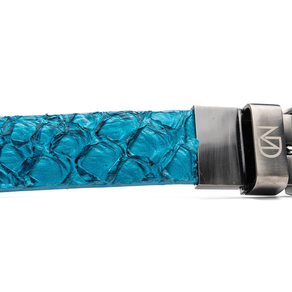 The Olivieri Belt Caribbean Blue by Marco Di Milano, made from genuine pirarucu with a textured turquoise finish and a silver logo buckle, is shown coiled on a white background.