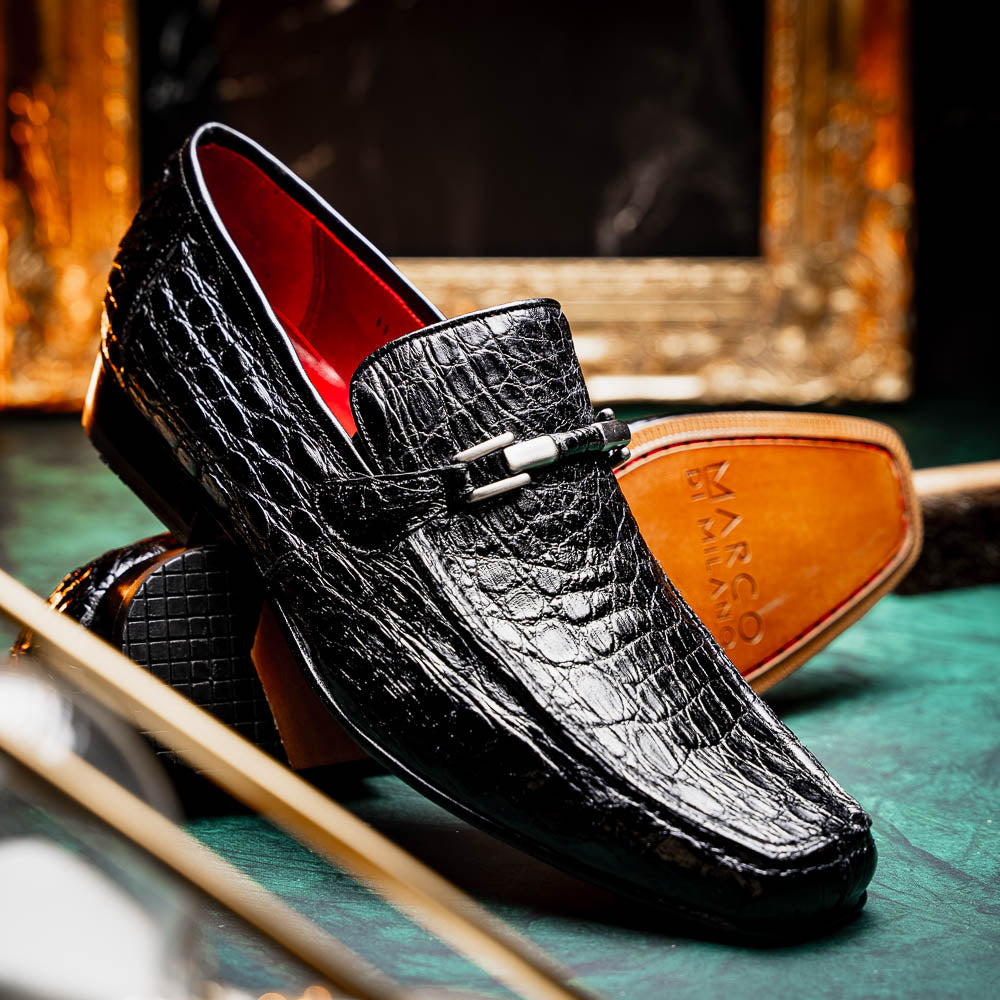 A pair of Fabro-Tin Black textured men's shoes by Marco Di Milano, featuring metal accents—one upright and one on its side showing the branded tan sole.