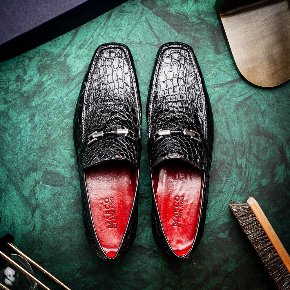 A pair of Fabro-Tin Black textured men's shoes by Marco Di Milano, featuring metal accents—one upright and one on its side showing the branded tan sole.