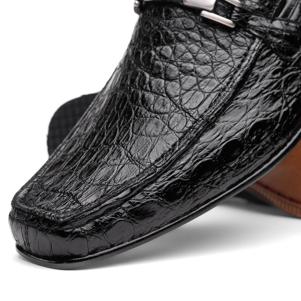 A pair of Fabro-Tin Black textured men's shoes by Marco Di Milano, featuring metal accents—one upright and one on its side showing the branded tan sole.