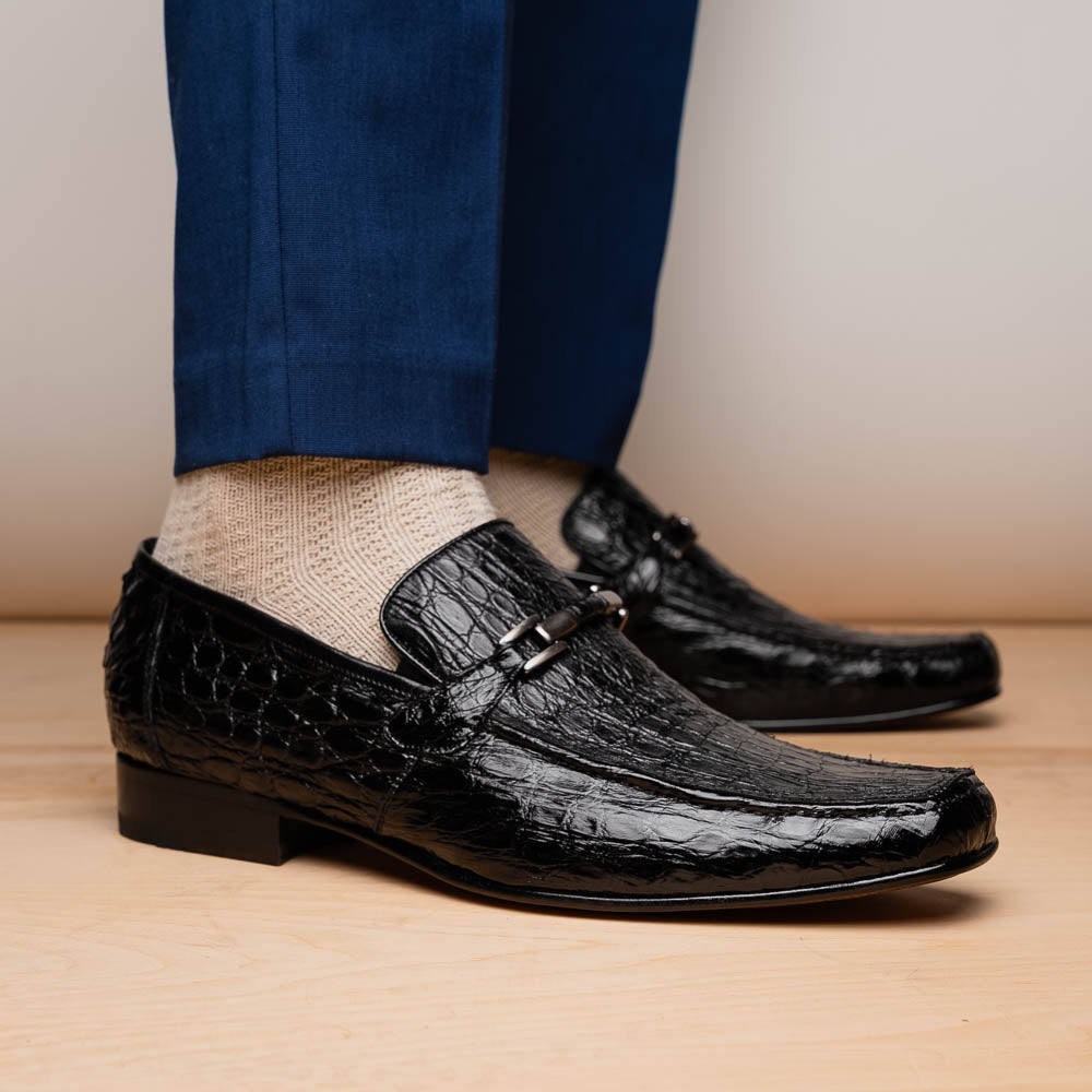 A pair of Fabro-Tin Black textured men's shoes by Marco Di Milano, featuring metal accents—one upright and one on its side showing the branded tan sole.
