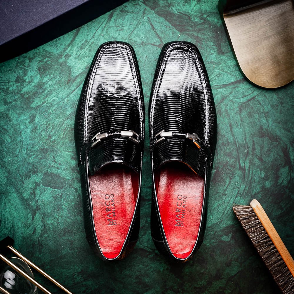 A pair of Marco Di Milano Fabro-Liz Black genuine lizard loafers, featuring textured leather, metal accents, and brown soles—one upright, the other on its side showing the luxury men's shoes branding on the sole.