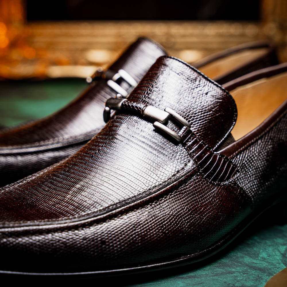 The Marco Di Milano Fabro-Liz Brown loafers feature a textured lizard finish, silver buckle detail, and tan leather soles—ideal for luxury footwear enthusiasts.