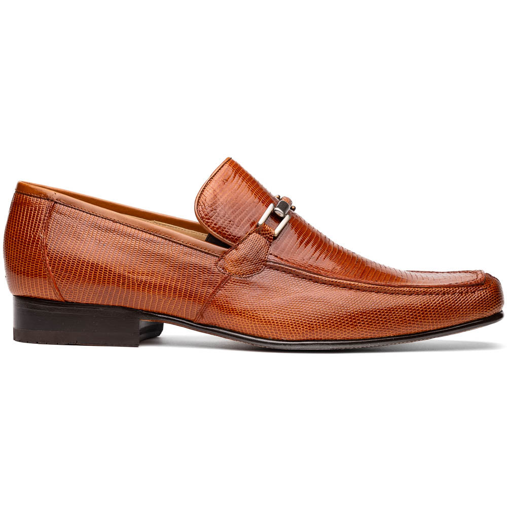 The Marco Di Milano Fabro-Liz Cognac loafers, crafted from brown leather with a textured finish and metal detail, are displayed—one upright and one showing the sole and branding—showcasing refined luxury footwear.