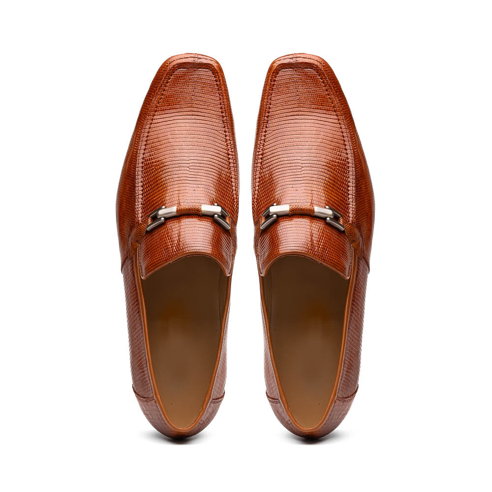 The Marco Di Milano Fabro-Liz Cognac loafers, crafted from brown leather with a textured finish and metal detail, are displayed—one upright and one showing the sole and branding—showcasing refined luxury footwear.
