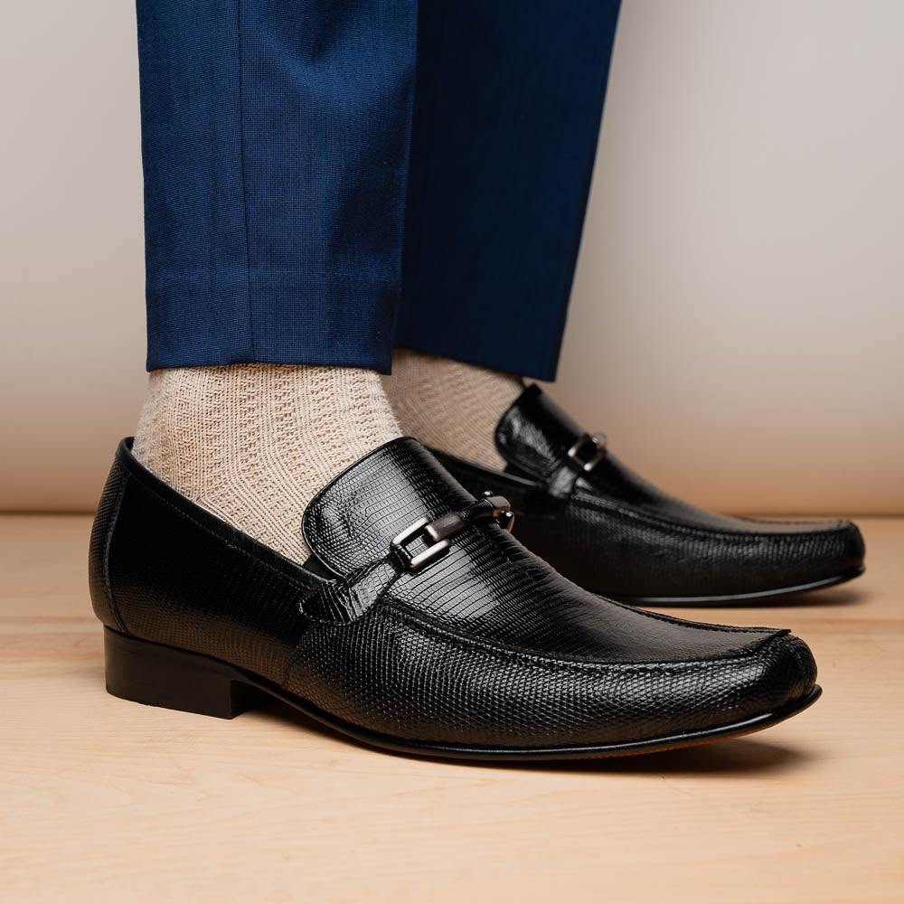 A pair of Marco Di Milano Fabro-Liz Black genuine lizard loafers, featuring textured leather, metal accents, and brown soles—one upright, the other on its side showing the luxury men's shoes branding on the sole.