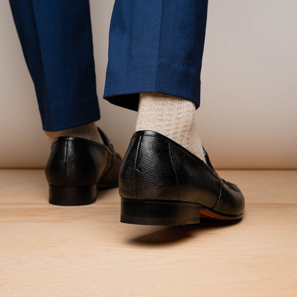A pair of Marco Di Milano Fabro-Liz Black genuine lizard loafers, featuring textured leather, metal accents, and brown soles—one upright, the other on its side showing the luxury men's shoes branding on the sole.