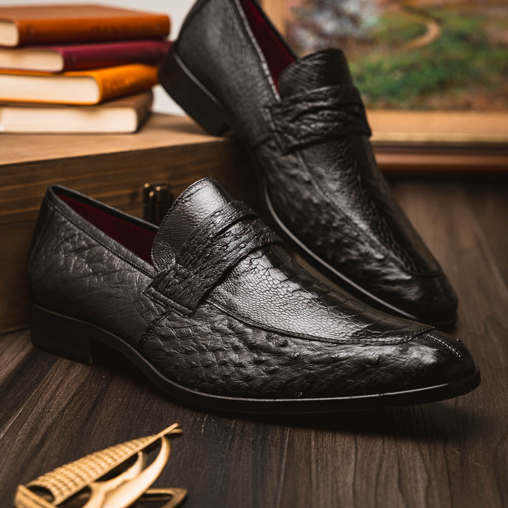 The Fangio Black by Marco Di Milano: a pair of black textured leather loafers, one upright and one sole-up, displaying the brand on the tan sole—luxury men's footwear to elevate any look.