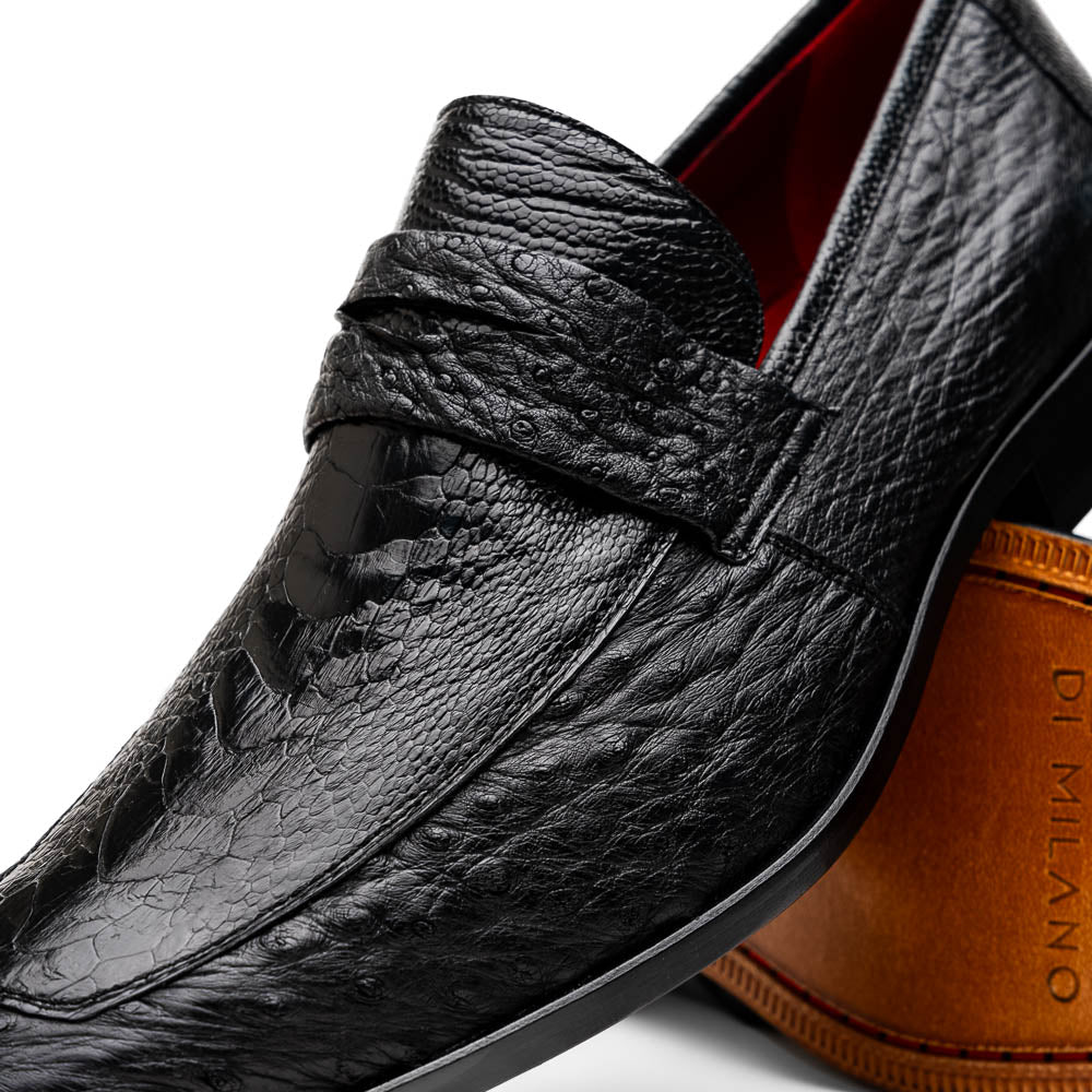 The Fangio Black by Marco Di Milano: a pair of black textured leather loafers, one upright and one sole-up, displaying the brand on the tan sole—luxury men's footwear to elevate any look.