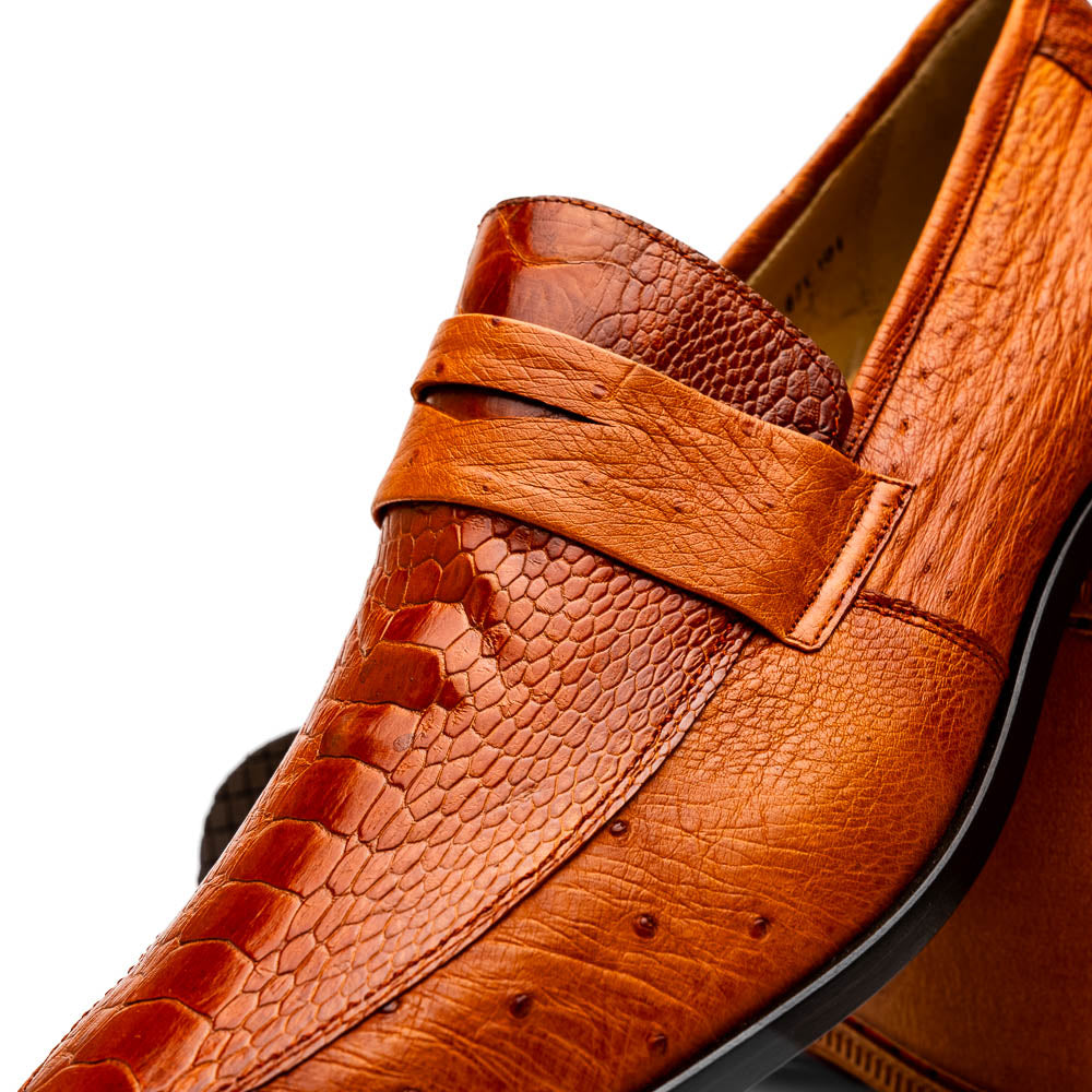 A pair of Marco Di Milano Fangio Cognac men's shoes in brown leather with textured detailing; one genuine ostrich loafer stands upright, while the other lies on its side showing the sole embossed with the brand name.