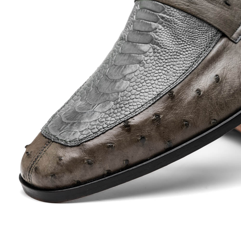 The Fangio Serpentine Gray by Marco Di Milano features gray textured leather in classic penny loafer style, with detailed stitching and tan leather soles—one shoe upright, one on its side—to showcase refined craftsmanship.