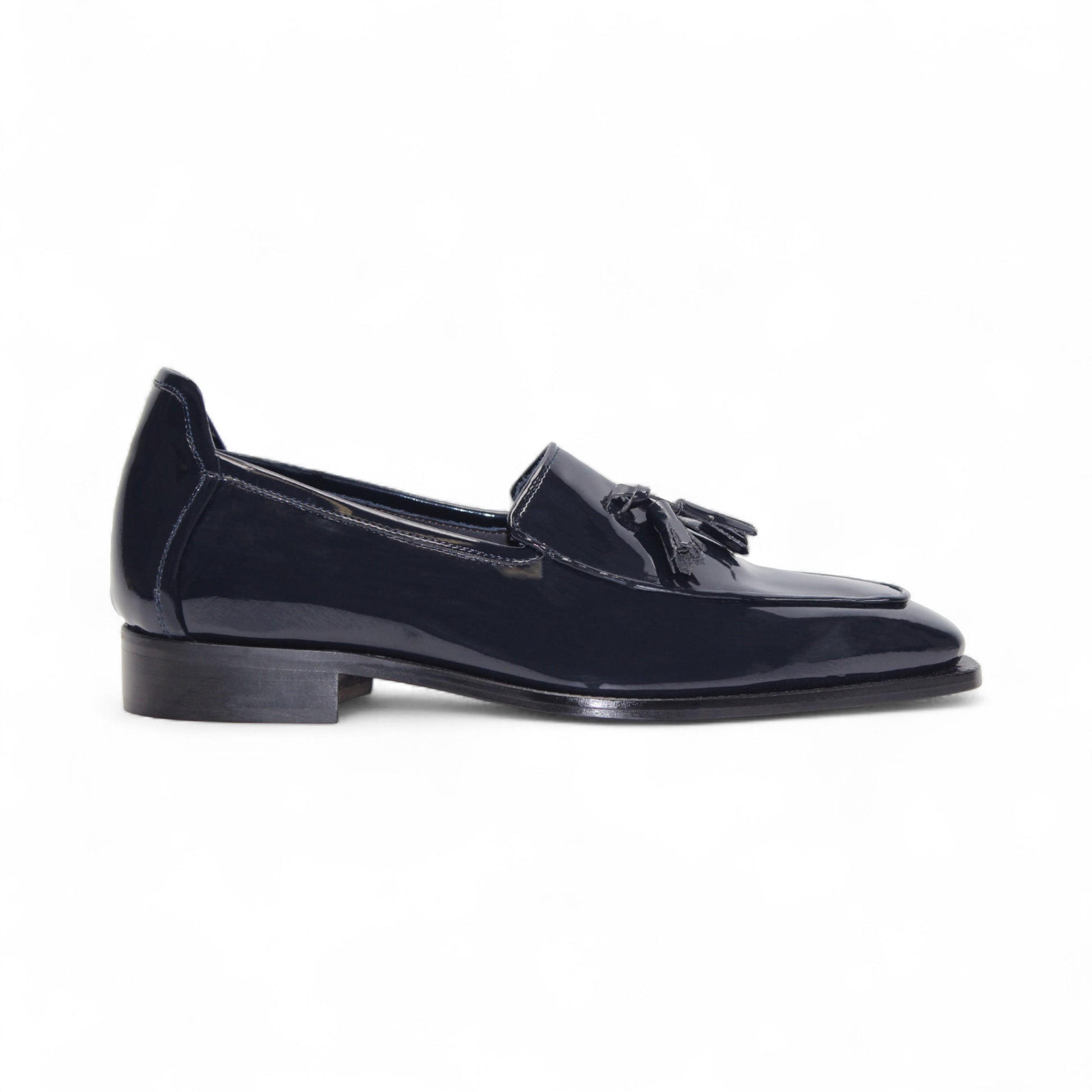 The Duca Di Matiste Duca Fano Navy loafer, featuring a tassel detail, low stacked heel, and almond toe in navy leather, showcases minimalist elegance in a side profile against a white background.