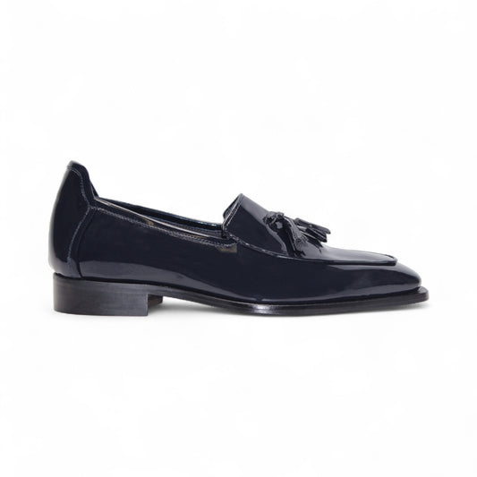 The Duca Di Matiste Duca Fano Navy loafer, featuring a tassel detail, low stacked heel, and almond toe in navy leather, showcases minimalist elegance in a side profile against a white background.