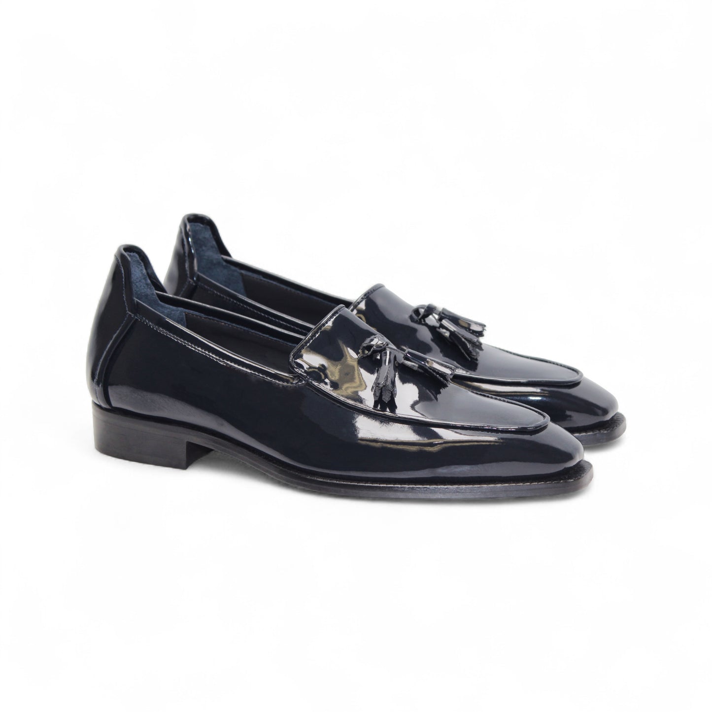 The Duca Di Matiste Duca Fano Navy loafer, featuring a tassel detail, low stacked heel, and almond toe in navy leather, showcases minimalist elegance in a side profile against a white background.