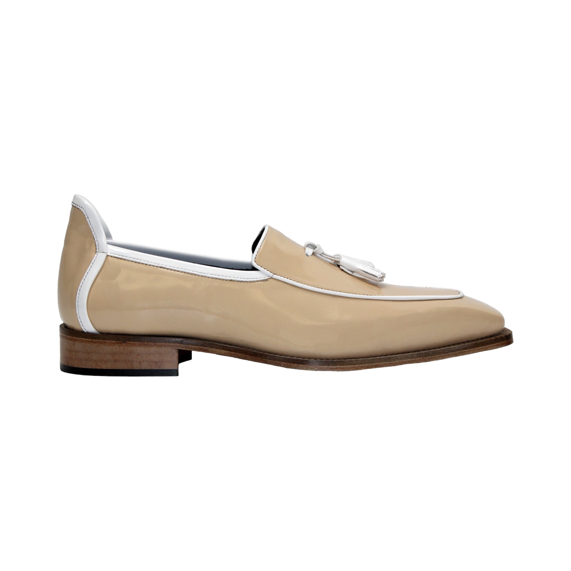 The Duca Di Matiste Duca Fano Cream/White loafer features beige patent leather, white trim, a wooden heel, and decorative tassels. This minimalist, elegant shoe is beautifully crafted in Italy. Shown in profile view.
