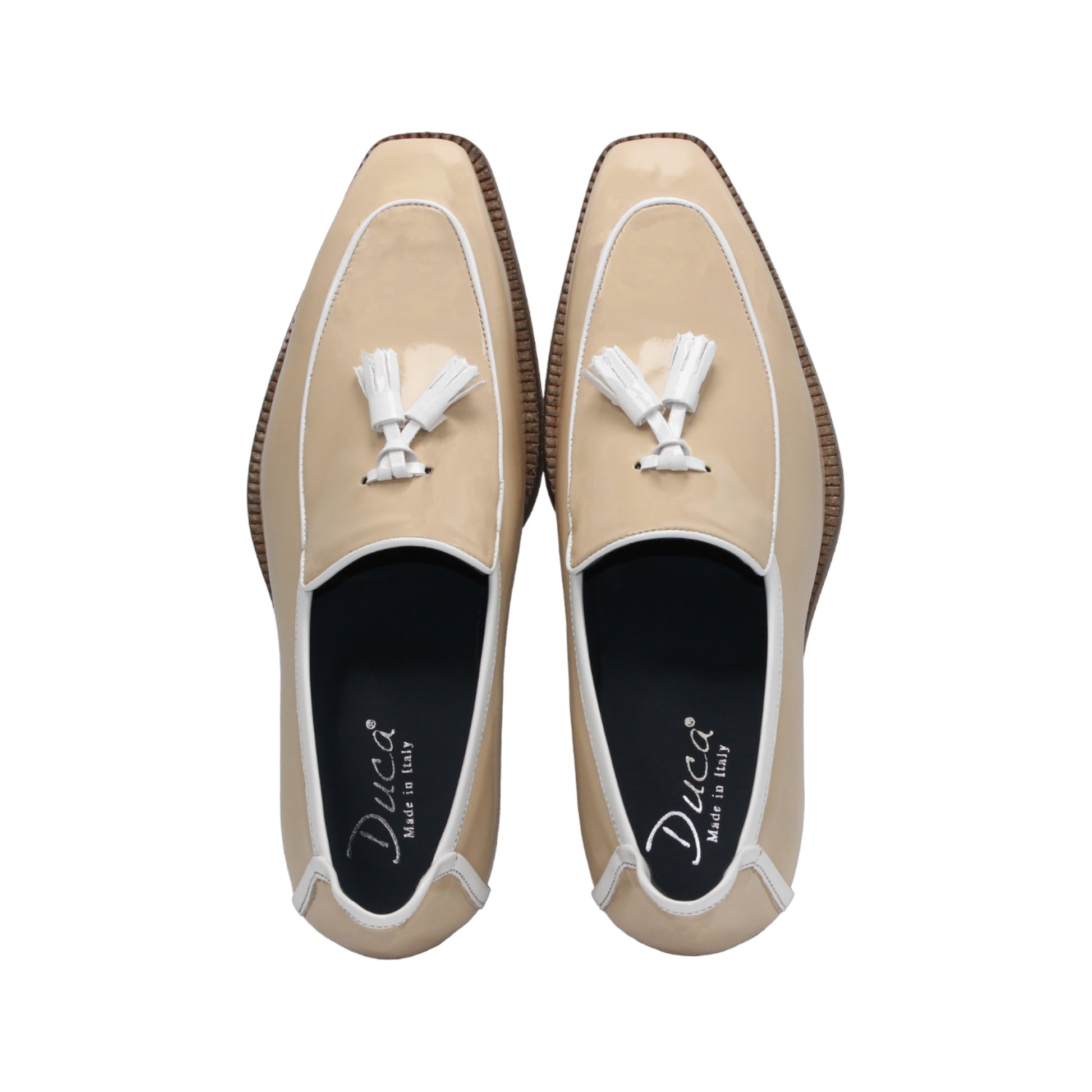 The Duca Di Matiste Duca Fano Cream/White loafer features beige patent leather, white trim, a wooden heel, and decorative tassels. This minimalist, elegant shoe is beautifully crafted in Italy. Shown in profile view.