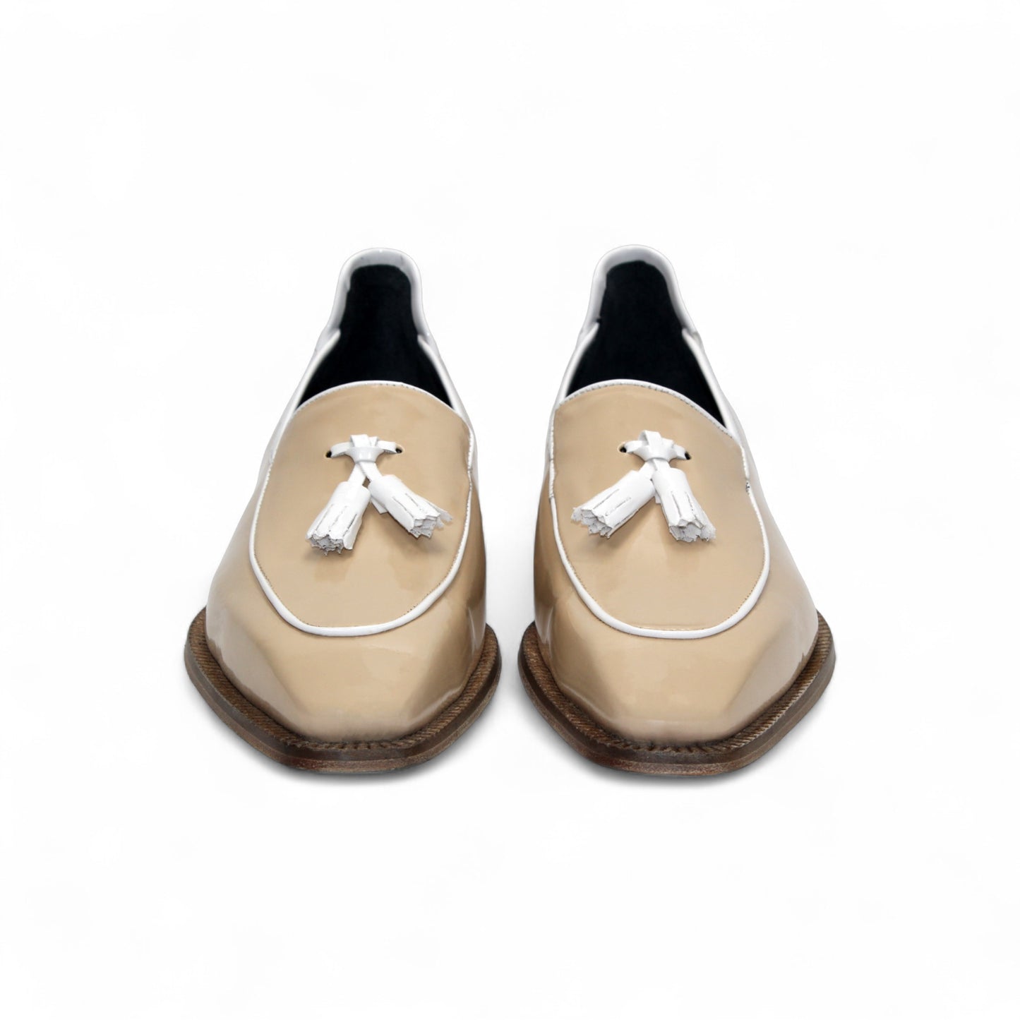 The Duca Di Matiste Duca Fano Cream/White loafer features beige patent leather, white trim, a wooden heel, and decorative tassels. This minimalist, elegant shoe is beautifully crafted in Italy. Shown in profile view.