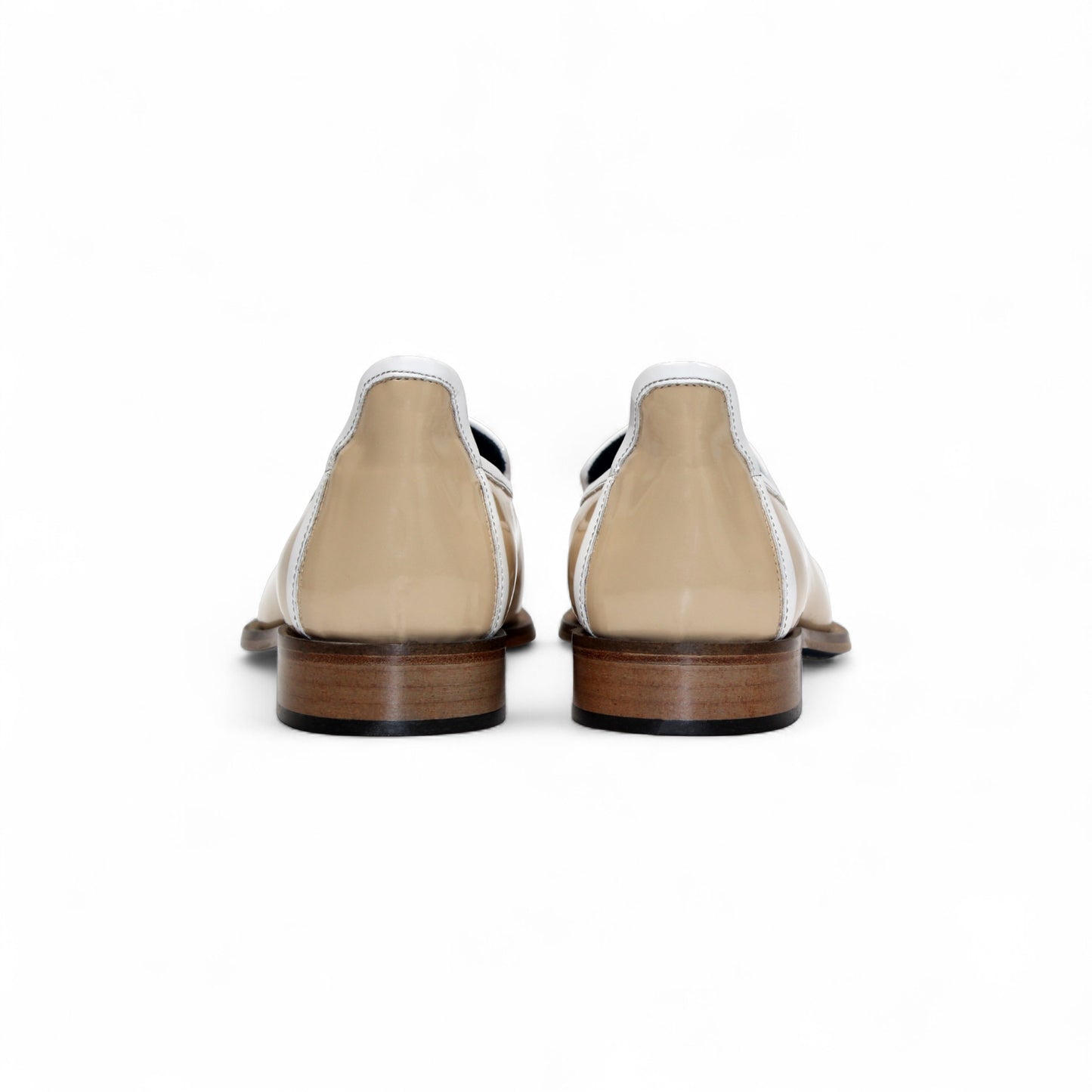 The Duca Di Matiste Duca Fano Cream/White loafer features beige patent leather, white trim, a wooden heel, and decorative tassels. This minimalist, elegant shoe is beautifully crafted in Italy. Shown in profile view.