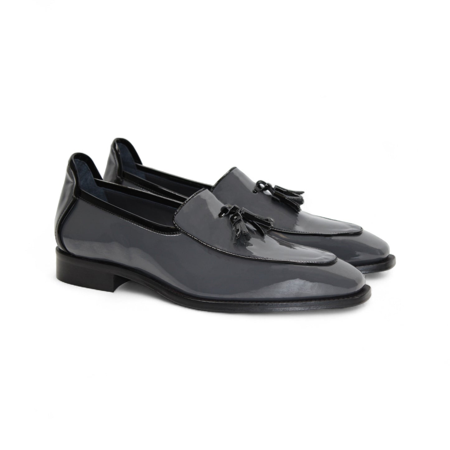 The Duca Di Matiste Duca Fano Grey/Black is an Italian-crafted glossy patent leather loafer with front tassel detail, low black heel, and black sole—showcasing minimalist luxury from every angle.