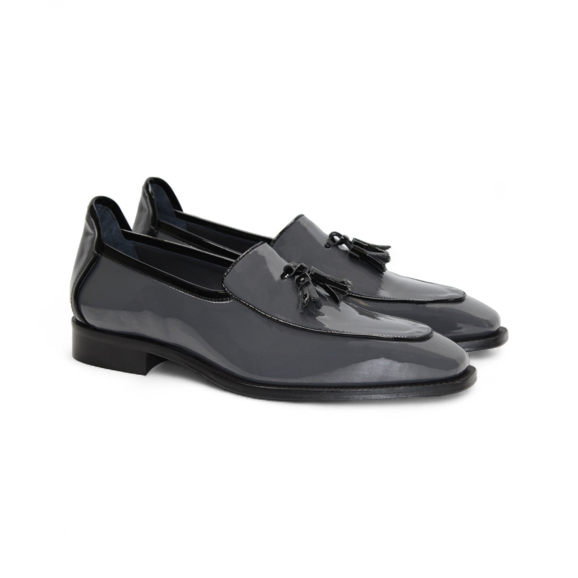 The Duca Di Matiste Duca Fano Grey/Black is an Italian-crafted glossy patent leather loafer with front tassel detail, low black heel, and black sole—showcasing minimalist luxury from every angle.