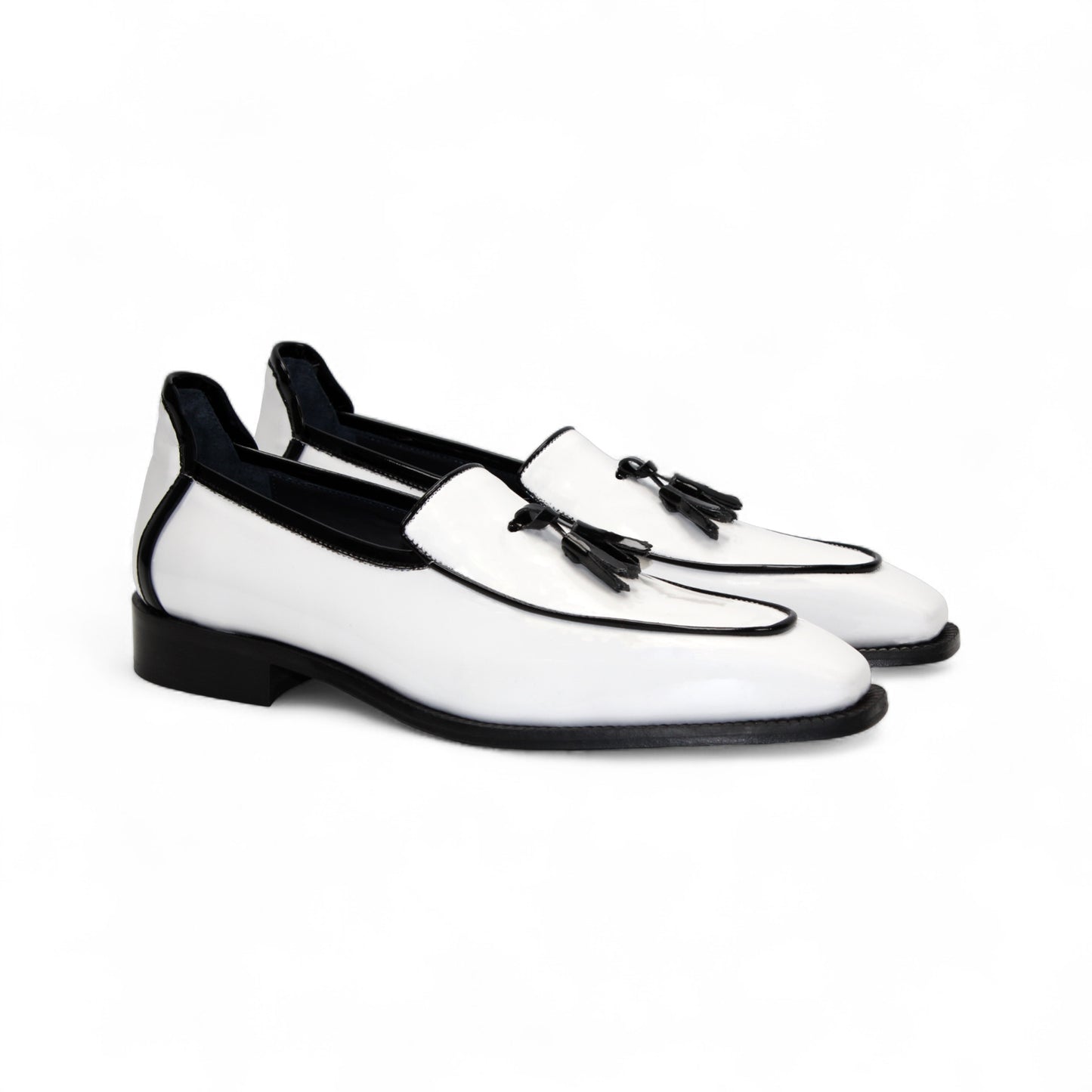 The Duca Di Matiste Duca Fano White/Black loafer features white patent leather, black trim, tassel detail, a low heel, and a glossy finish—shown minimalist style on a plain white background.