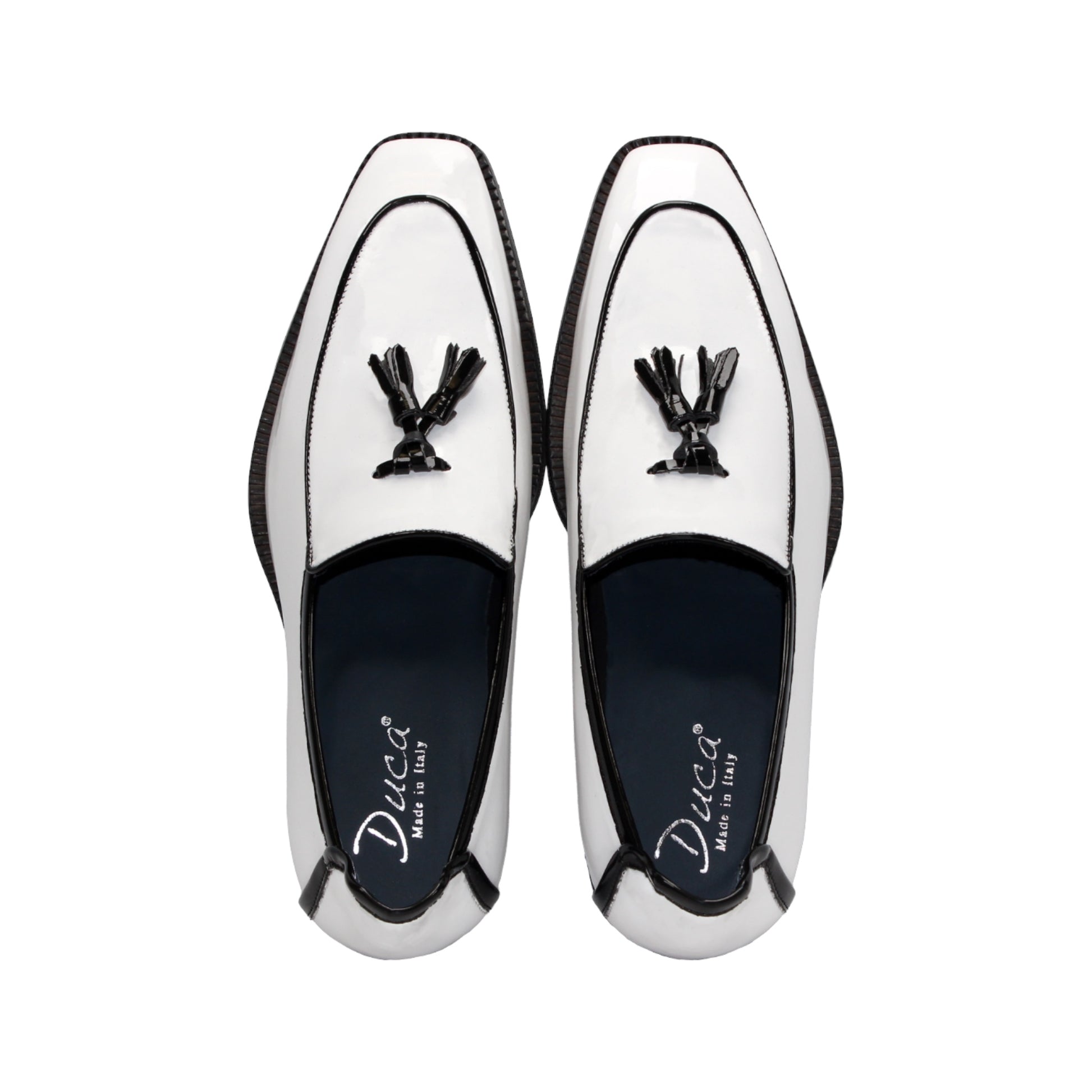 The Duca Di Matiste Duca Fano White/Black loafer features white patent leather, black trim, tassel detail, a low heel, and a glossy finish—shown minimalist style on a plain white background.