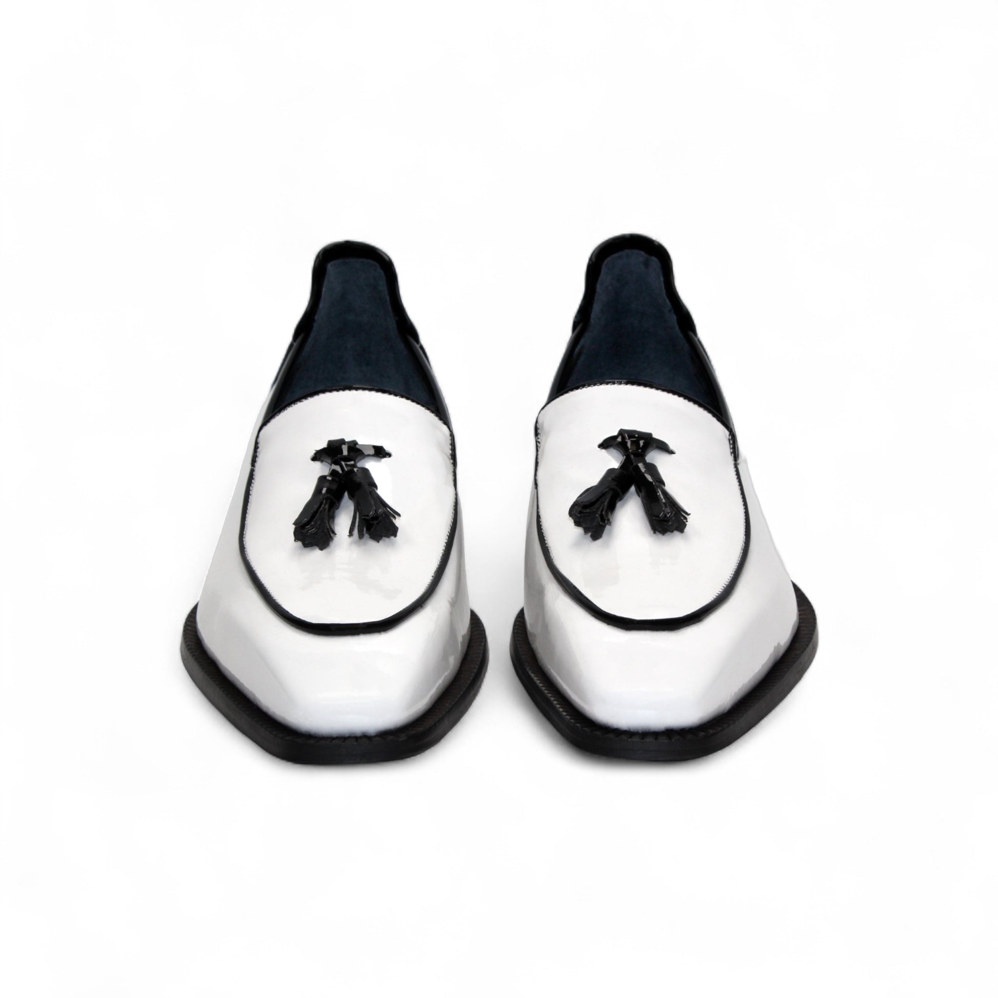 The Duca Di Matiste Duca Fano White/Black loafer features white patent leather, black trim, tassel detail, a low heel, and a glossy finish—shown minimalist style on a plain white background.