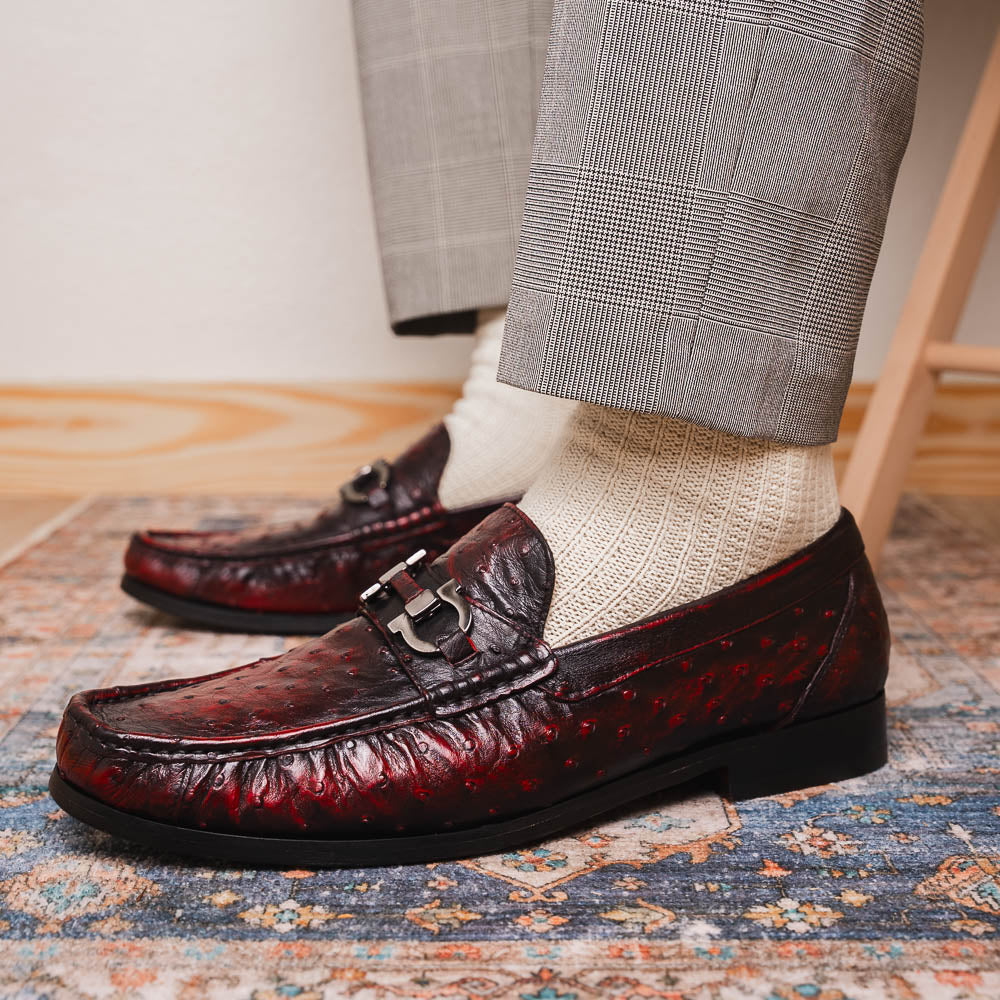 The Marco Di Milano Ferrioni BlackCherry loafers, shown with one upright and one on its side to reveal the sole, feature classic metal bit detailing—ideal for those seeking luxury men's footwear.