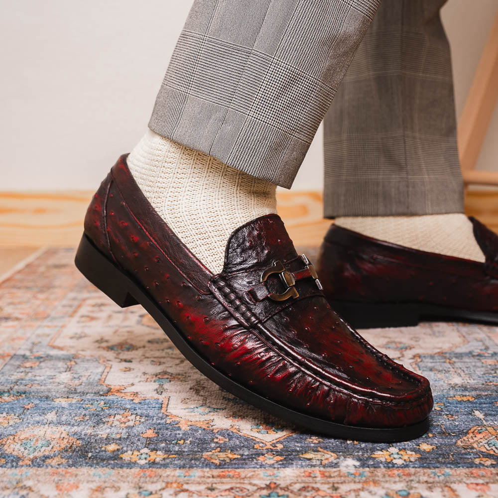 The Marco Di Milano Ferrioni BlackCherry loafers, shown with one upright and one on its side to reveal the sole, feature classic metal bit detailing—ideal for those seeking luxury men's footwear.