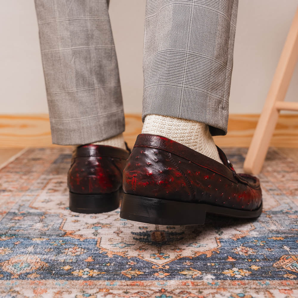 The Marco Di Milano Ferrioni BlackCherry loafers, shown with one upright and one on its side to reveal the sole, feature classic metal bit detailing—ideal for those seeking luxury men's footwear.
