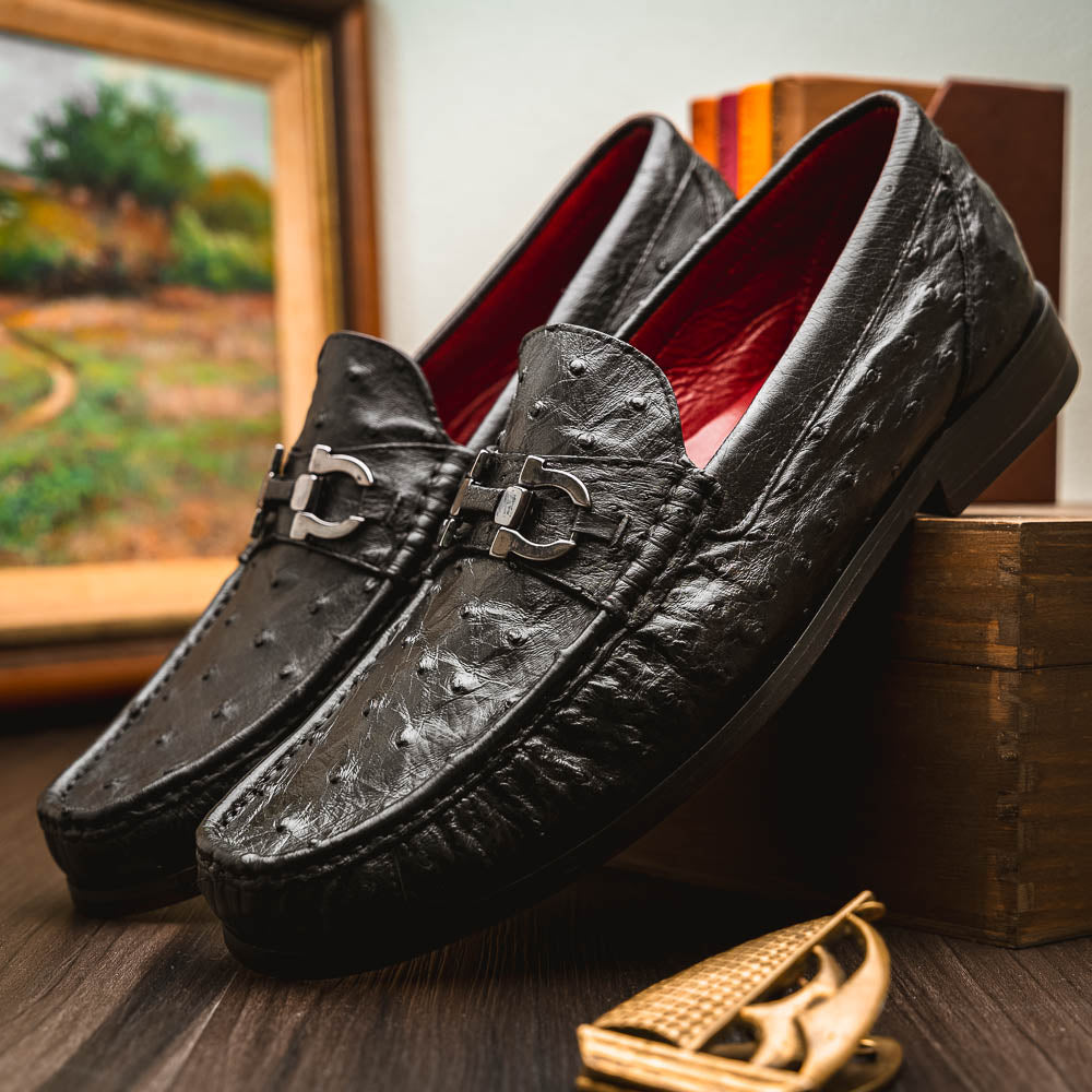 The Marco Di Milano Ferrioni Black: luxury men's loafers in genuine ostrich leather with metal buckles and brown soles, shown both upright and on their side to highlight the branding.