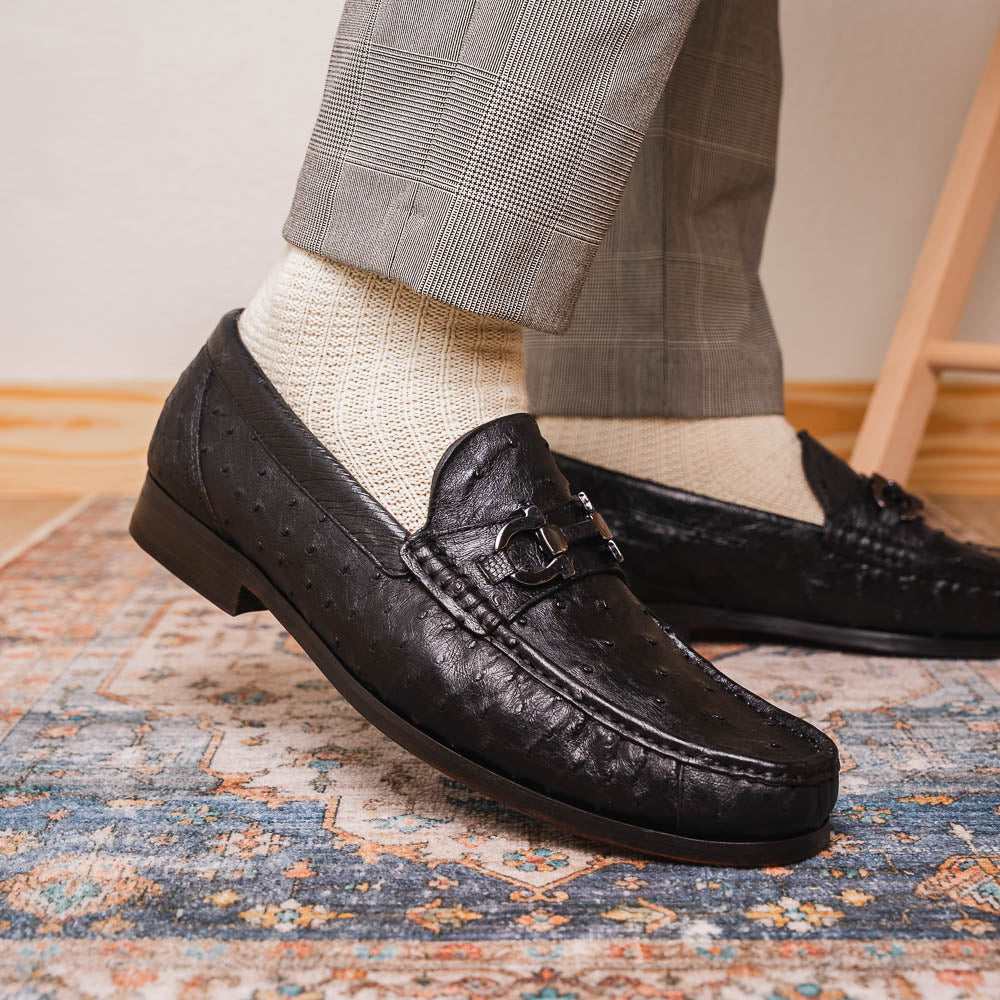 The Marco Di Milano Ferrioni Black: luxury men's loafers in genuine ostrich leather with metal buckles and brown soles, shown both upright and on their side to highlight the branding.