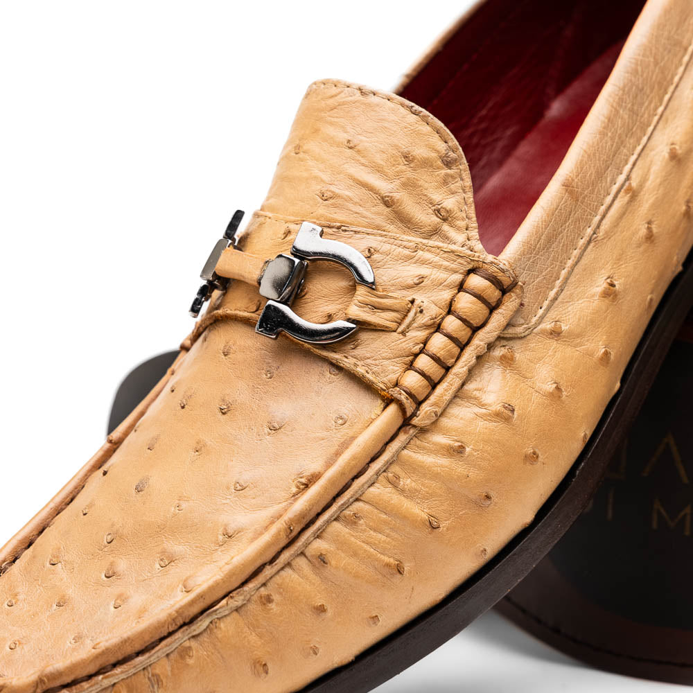 The Marco Di Milano Ferrioni Orix is a pair of genuine beige ostrich loafers with a classic bit buckle, one upright and one on its side showing the insole logo—timeless luxury men's footwear.