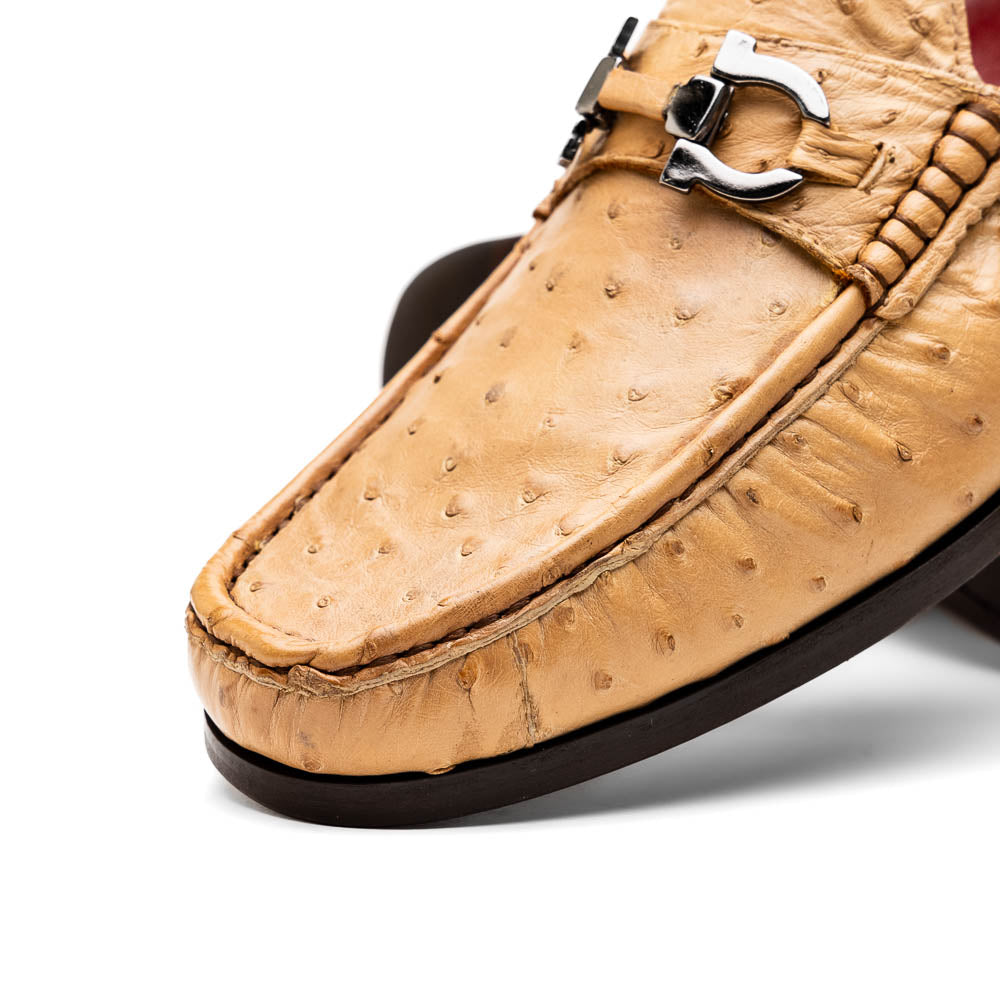 The Marco Di Milano Ferrioni Orix is a pair of genuine beige ostrich loafers with a classic bit buckle, one upright and one on its side showing the insole logo—timeless luxury men's footwear.