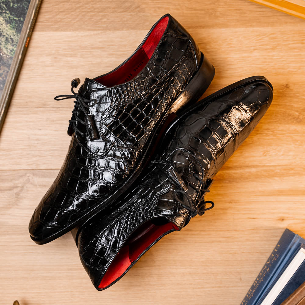 The Fitipaldi Black by Marco Di Milano: luxury black crocodile-patterned leather dress shoes with laces, one upright and one sole up to reveal a hand-painted orange-brown sole.