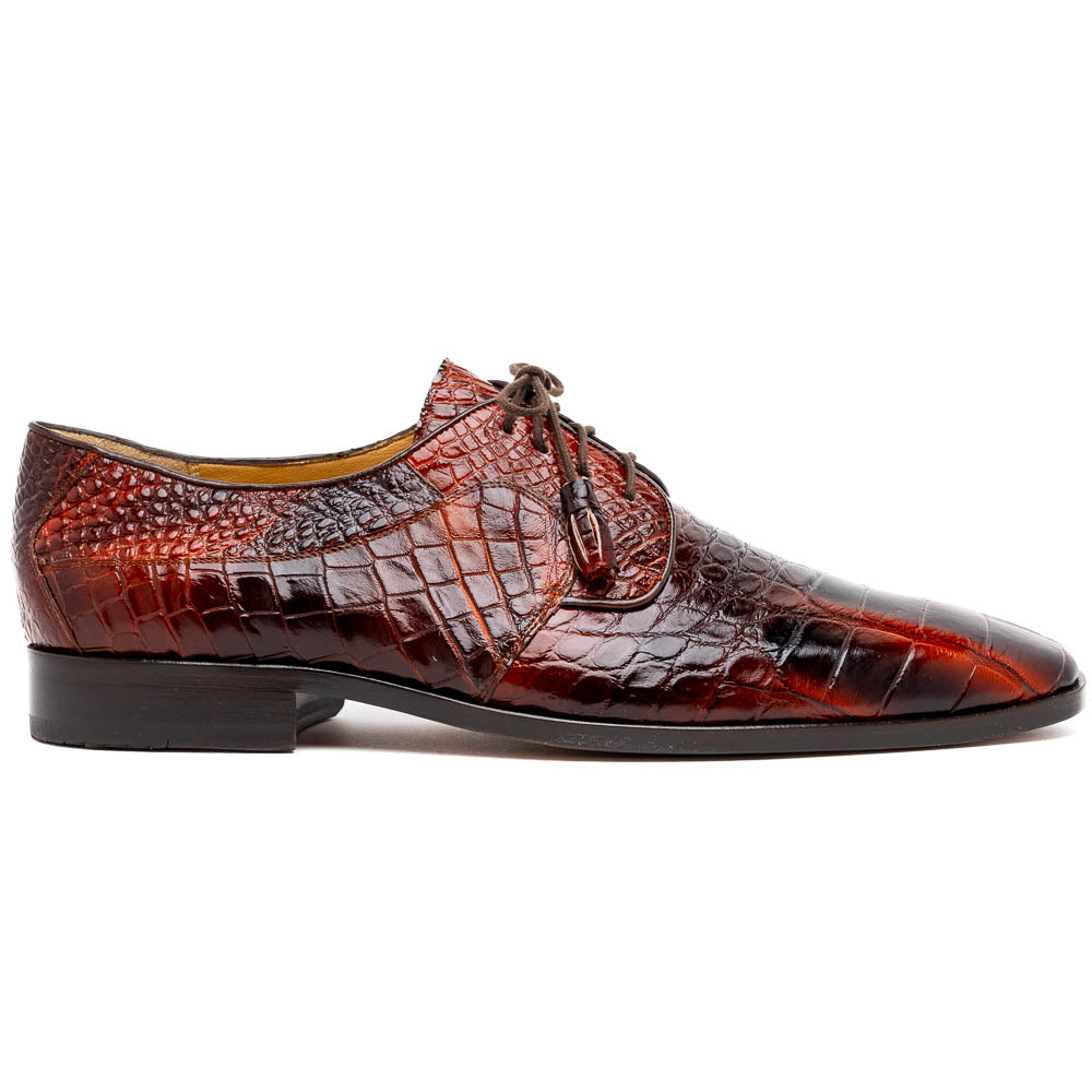 A pair of Fitipaldi Rustic Cognac shoes by Marco Di Milano in brown crocodile-patterned leather—one upright, one displaying the sole with branding—showcases exquisite hand-painted finishes, epitomizing luxury footwear.