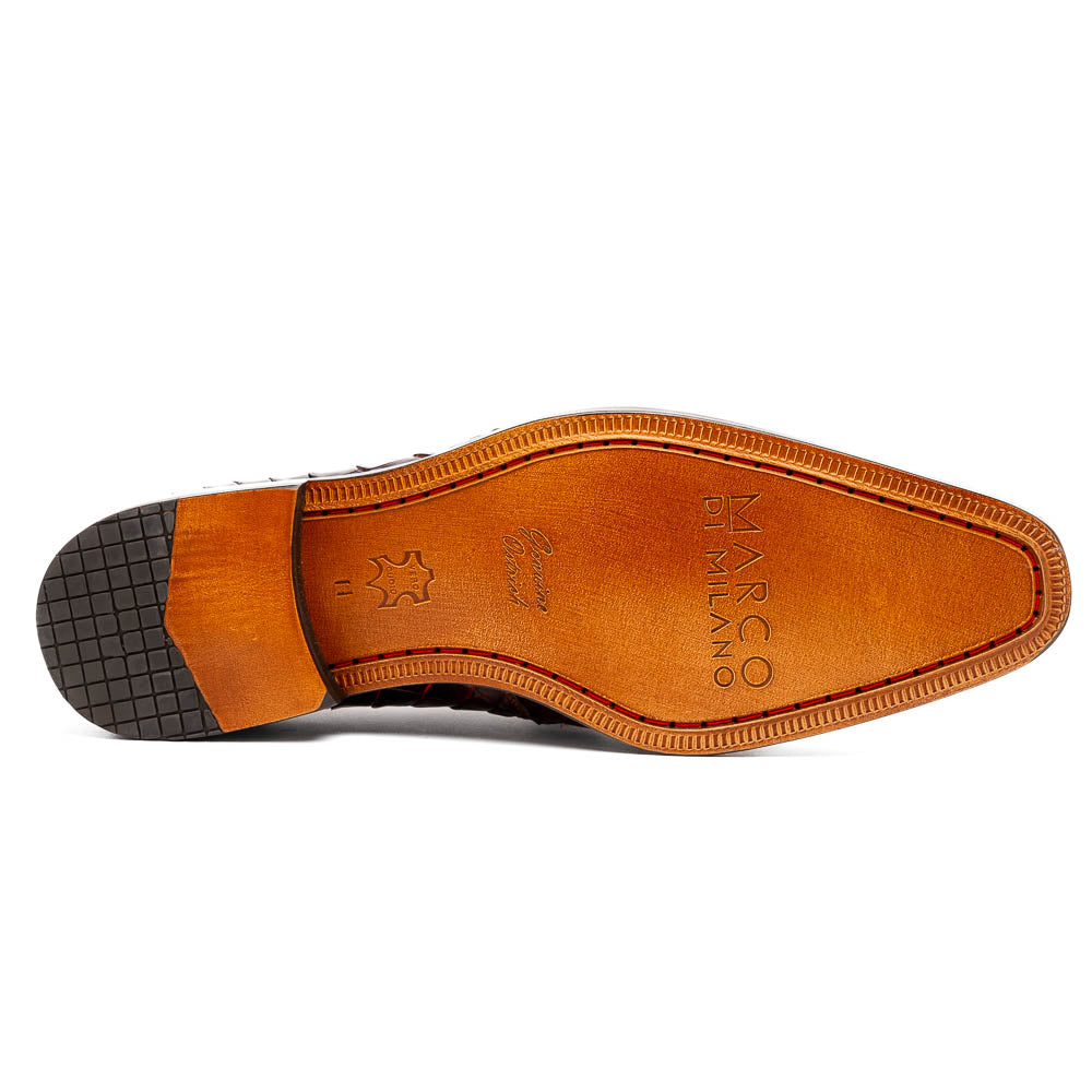 A pair of Fitipaldi Rustic Cognac shoes by Marco Di Milano in brown crocodile-patterned leather—one upright, one displaying the sole with branding—showcases exquisite hand-painted finishes, epitomizing luxury footwear.